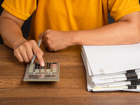 Person using calculator beside stack of documents