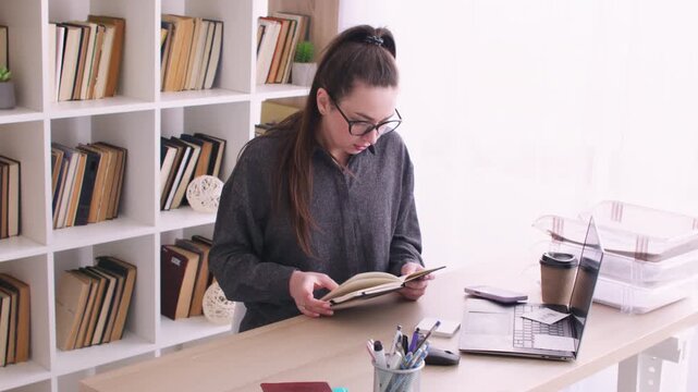 Professional lifestyle. Low productivity. Bored female employee at desk with laptop notebook analyzing business paperwork at modern workspace.