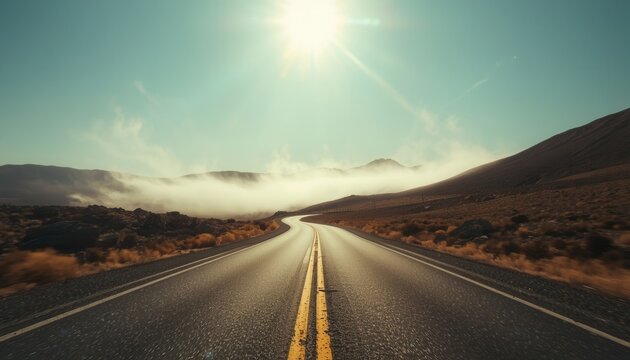 Open Road to the Horizon: An empty asphalt road stretches towards a vast, sunlit horizon, flanked by arid hills and kissed by wisps of low-lying fog, embodying freedom and journey