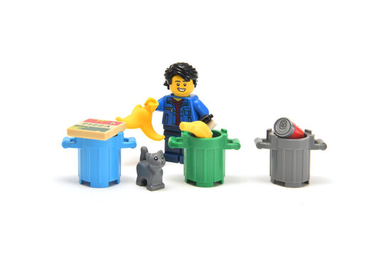 Lego minifigure isremoving a garbage of different materials isolated on white background. Editorial illustrative image of popular plastic toy.
