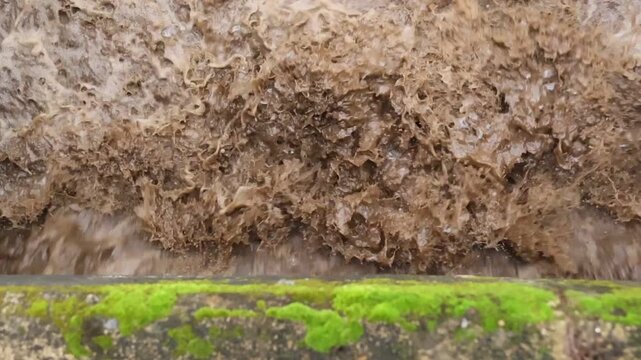 Mossy Rock Texture with Flowing Water Creating Natural Abstract Pattern, Earthy Brown Surface, Weathered Stone Ledge, Rugged Overhang, Vivid Green Moss Growth Beneath Waterfall in Damp Outdoor Setting