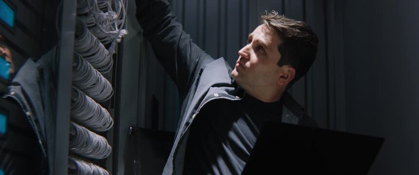 Exhausted Male Network Engineer Reacting to Critical Server Crash or Cyber Attack Late at Night. Concept of IT Burnout, Network Downtime, Data Loss Stress, and Severe Infrastructure Emergencies.