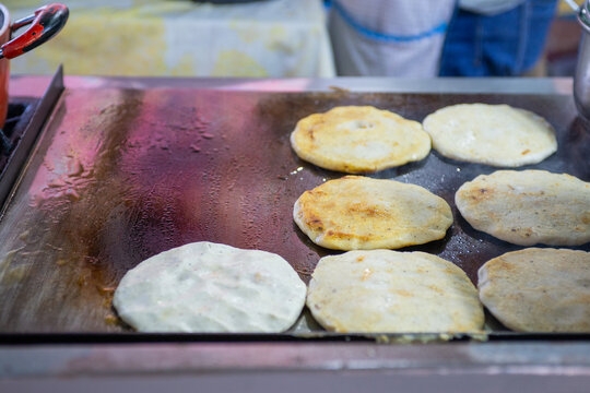 Pupusas Cooking on a Greased Griddle at a Street Food Stall
