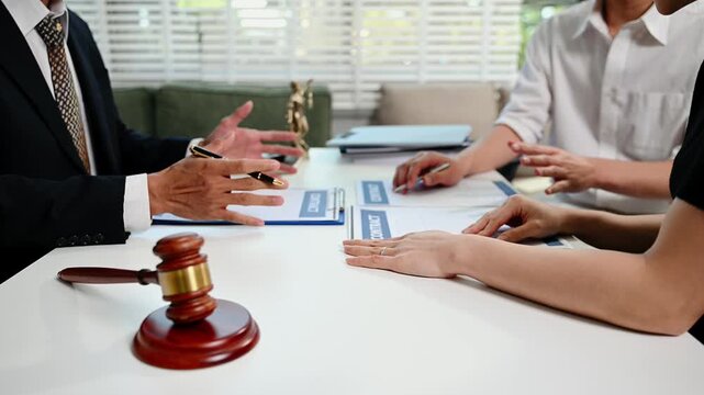 Unidentifiable couple having a serious discussion with a lawyer over a divorce contract.