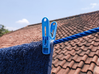 Blue plastic laundry peg attached to clothesline rope, essential household tool for drying clothes outside. © Day Dreamer 59