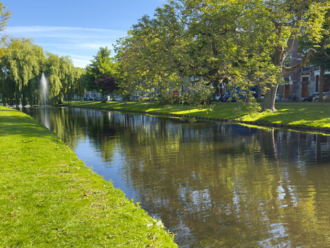 Sunny canal park with fountain and tree reflections in Rotterdam Delfshaven Netherlands