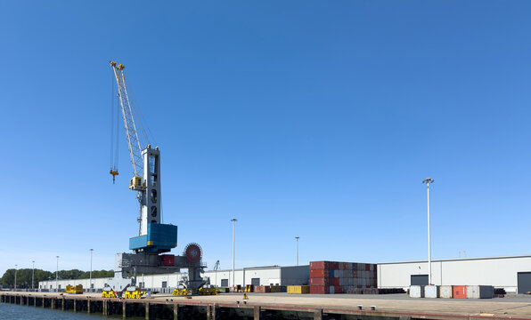 Dockside crane and stacked containers at Waalhaven Pier 6 in Rotterdam, Netherlands under blue sky