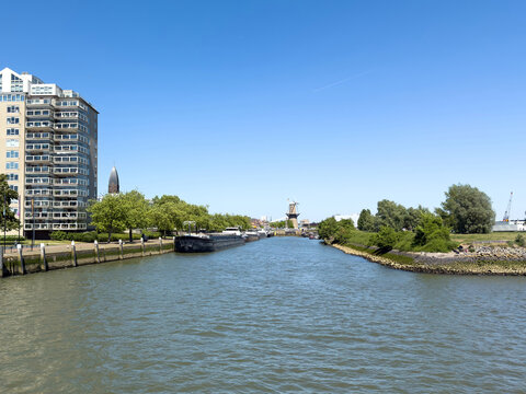 Moored barges along the Voorhaven waterfront in Schiedam, Netherlands, near De Nolet windmill