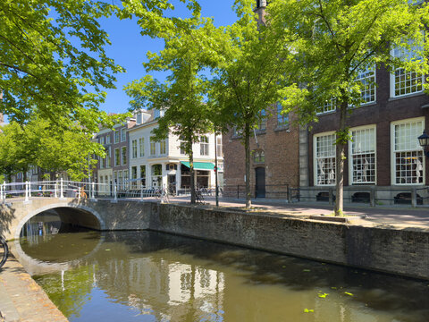 Historic canal houses and arched bridge in Delft City Centre on sunny spring day, Netherlands