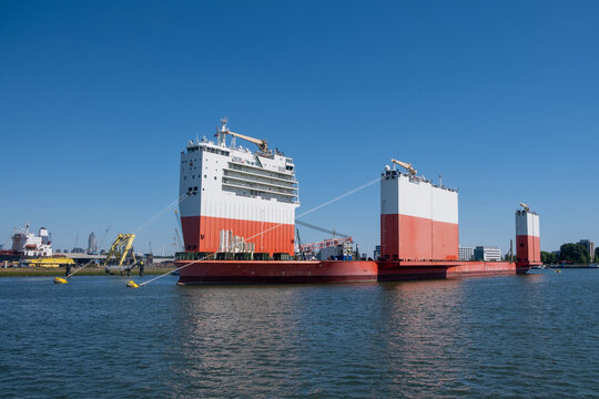 Red and white heavy lift vessel moored in Rotterdam harbor, Netherlands, blue sky