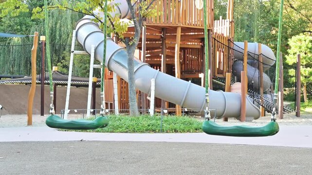 야외 어린이 놀이터에 있는 빈 초록색 그네와 미끄럼틀 놀이기구(Empty green swings and slide play equipment at outdoor children playground in Korea)