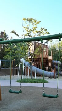 야외 어린이 놀이터에 있는 빈 초록색 그네와 미끄럼틀 놀이기구(Empty green swings and slide play equipment at outdoor children playground in Korea)