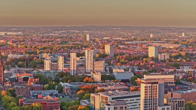 Coventry skyline of tower blocks, office buildings and rooftops in soft evening light in the West Midlands, England, drone lateral slide right