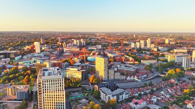 Coventry tower blocks, terraced streets and rooftops in golden hour light near the city centre in the West Midlands, England, drone lateral slide right