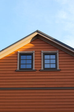 modern wooden house with orange plank facade and two small windows on the attic