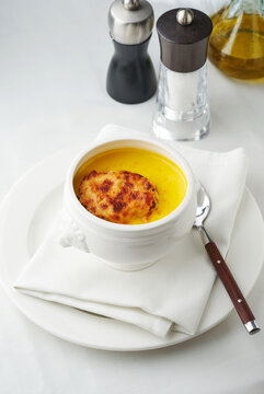 Soup with cheese crust served in white bowl on napkin, gourmet dining concept