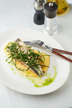 Grilled fish with sea greens and nut garnish, modern dining concept, restaurant menu inspiration