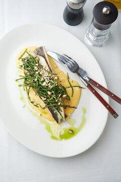 Seared fish fillet with greens and almond sauce, fine dining experience, gourmet restaurant menu option