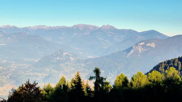 Mountain panorama overlooking treetop peaks under a blue sky seen from Monte Bondone in Trentino, Northern Italy
