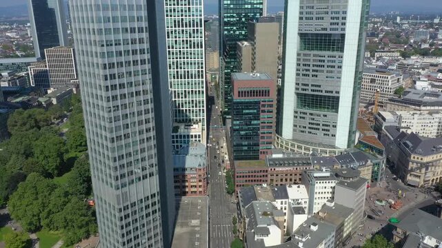 Aerial drone view flying between modern glass skyscrapers in Frankfurt am Main, Germany, showcasing the financial district, contemporary architecture and urban streets.