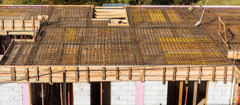 Steel reinforcement mesh and wooden formwork prepared for concrete pouring on a building floor slab under construction, showing structural engineering and foundation work.