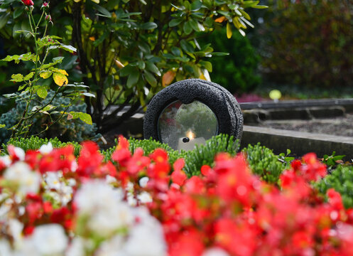 Steinernes Grablicht hinter bl&uuml;henden Blumen auf dem Kettwiger Friedhof