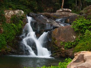 Beautiful tiered waterfall cascading over large boulders into forest pool © wannasak