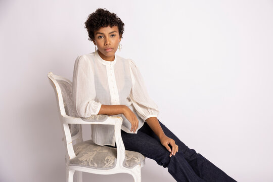 Young Hispanic woman sitting on white antique wooden chair