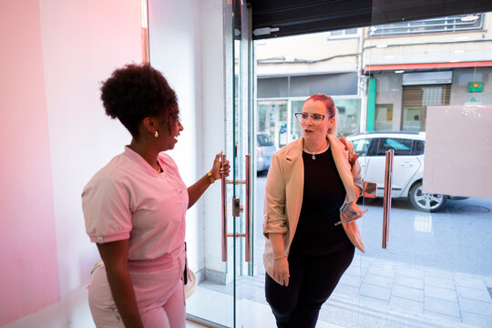 Healthcare worker welcoming a woman into a medical clinic