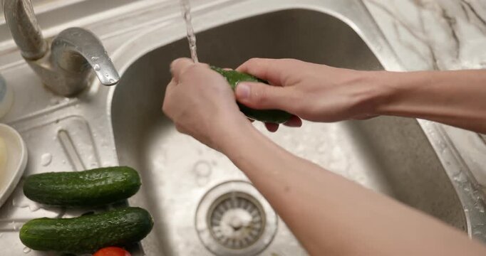 Close-up male hand wash rinse cucumber under tap water in sink. 4K 10-bit