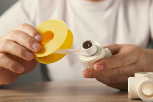 Plumber fixing pipe fittings with screwdriver at table, closeup