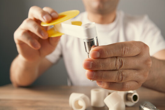 Plumber fixing pipe fittings with screwdriver at table, closeup