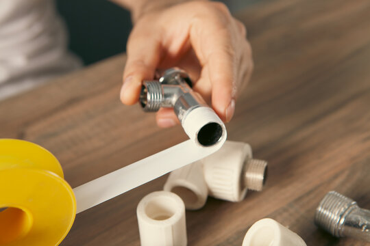 Plumber fixing pipe fittings with screwdriver at table, closeup