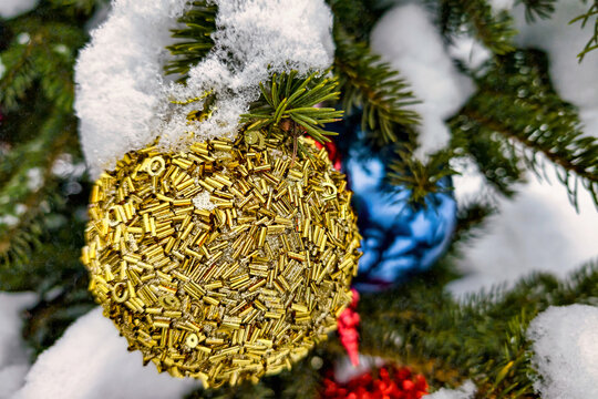 A Christmas and New Year tree stands in snow, adorned with colorful ornaments. The branches are covered with white snow, adding to the festive look