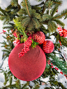 A Christmas and New Year tree is covered in snow and decorated with red ornaments and green branches in a winter setting