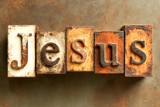 Blocks used to spell out Jesus are placed on a rough surface. The blocks show signs of age with rust and wear visible. The display captures a sense of history