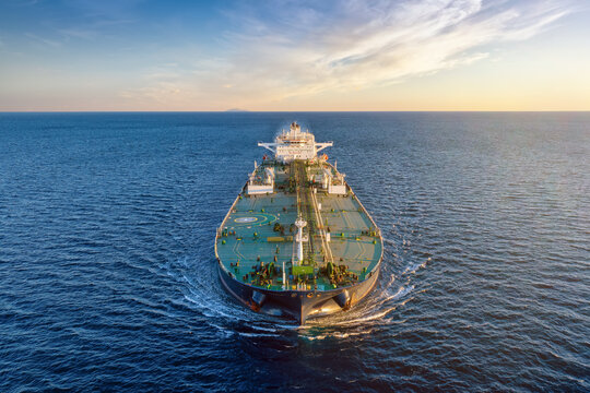 Front view of a heavy loaded crude oil tanker ship sailing over the ocean during sunset time as a concept for transport and logistics