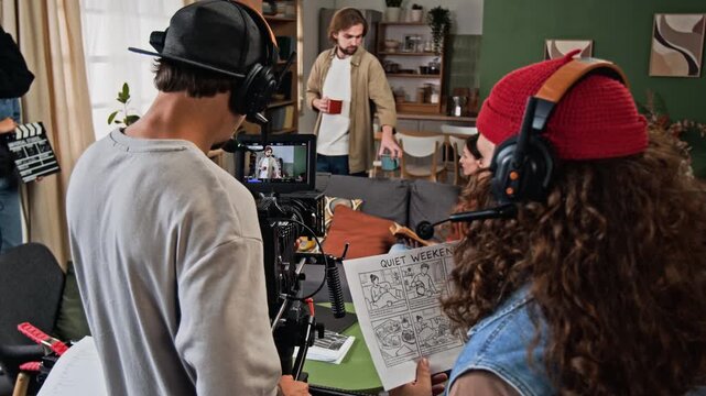 Young adult Caucasian film crew filming actors on set with cinema camera during studio production. Clip suitable for cinematography and video industry projects