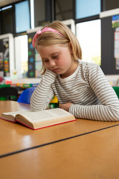 Schoolgirl reading a book in the classroom