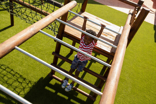 Schoolboy playing on horizontal ladder in the school playground