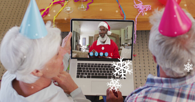 Image of snow falling text over senior caucasian couple on laptop image call at christmas