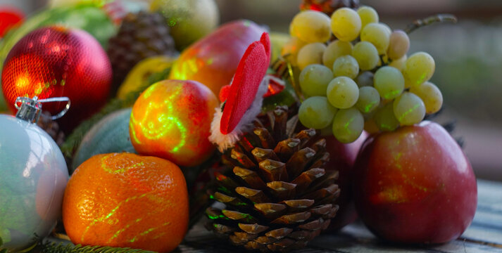 Close-up of Christmas ornaments and fresh fruits on a festive table.