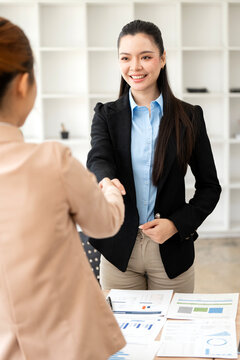 Asian Businesswoman Smiling and Handshaking in Vertical Office Meeting