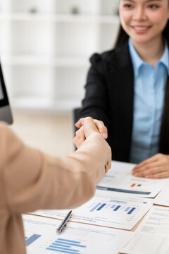Vertical Close Up of Businesswomen Handshake over Financial Documents on Desk