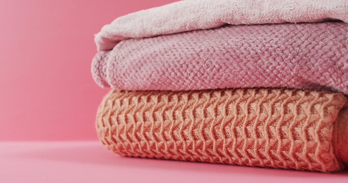 Image of folded blankets lying on pink background