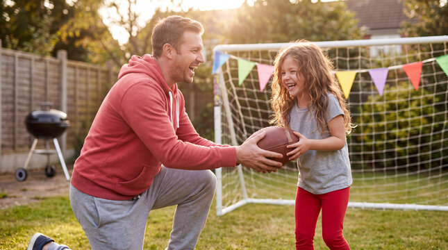 Father kneeling to pass a football to his daughter in a festive backyard for Big Game Party promotions.