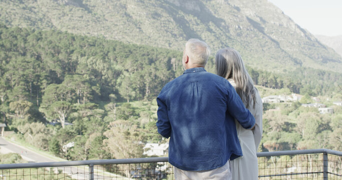 Happy middle aged caucasian couple talking and embracing on terrace in mountains, slow motion