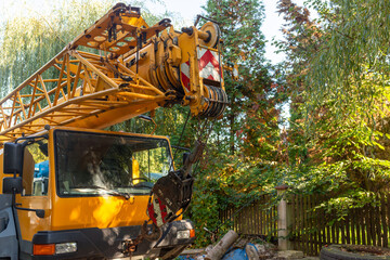 Yellow truck-mounted mobile crane with a lattice boom, multiple cable sheaves and suspended hook block. Heavy construction machinery photographed outdoors, illustrating industrial lifting technology,  © Volha