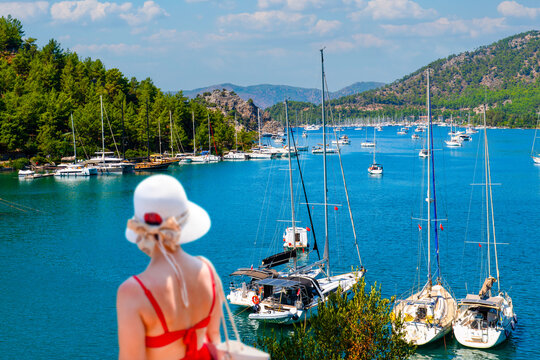 Female tourist looking at yachts and sailboats in Orhaniye bay near Kizkumu beach, Marmaris, Mugla, Turkey