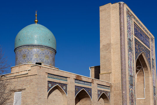 Barak Khan Madrasah in Tashkent featuring a turquoise dome and ornate tilework against a clear blue sky. Historic Islamic architecture of Uzbekistan ideal for travel publications and cultural.